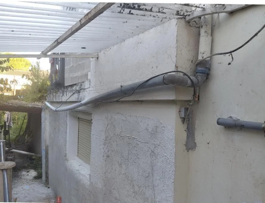 Eaux pluviales rejetées au pied du mur avec humidité sur la maçonnerie